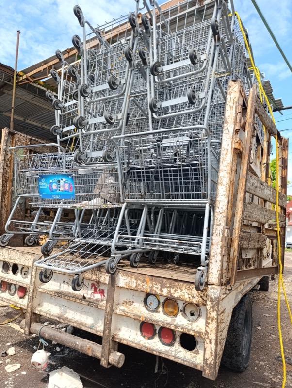 Carritos metálicos apilados y asegurados en la plataforma del camión de recolección