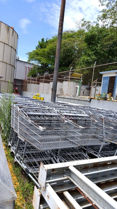 Carritos metálicos apilados en el patio de acopio, junto a tanques de almacenamiento industrial
